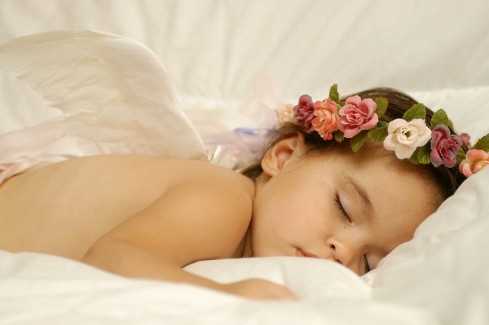Little girl with wings and flower crown sleeping