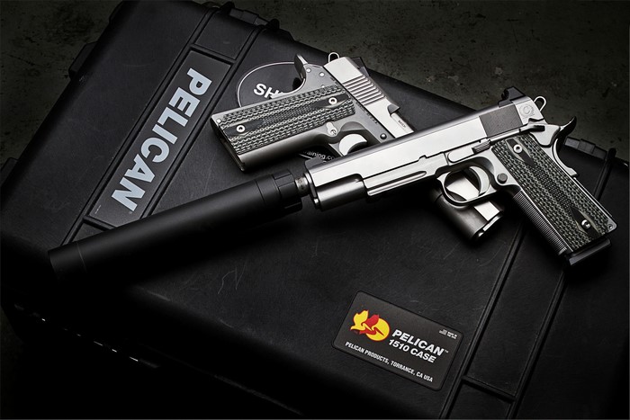 Two Colt 1911 pistols with suppressors on a Pelican case