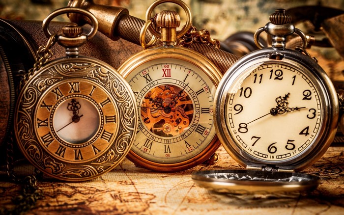 Three antique pocket watches on a map