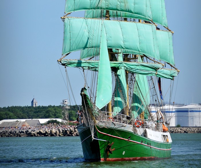 Green sailing ship with turquoise sails on the water