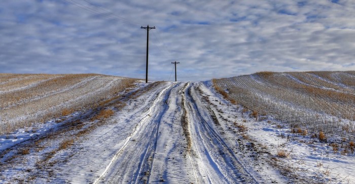 Snowy road with power lines on a hill