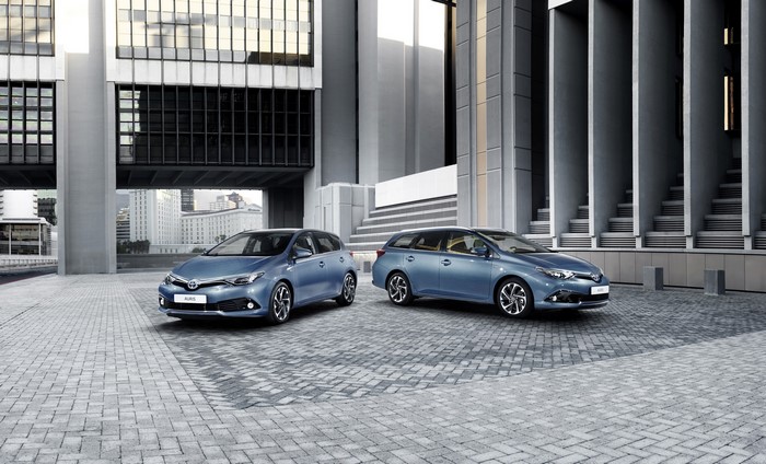 Two light blue Toyota Auris cars parked outside a modern building