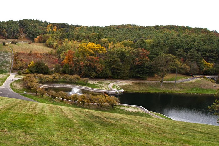 Autumn foliage around a pond with a fountain in Clinton, USA