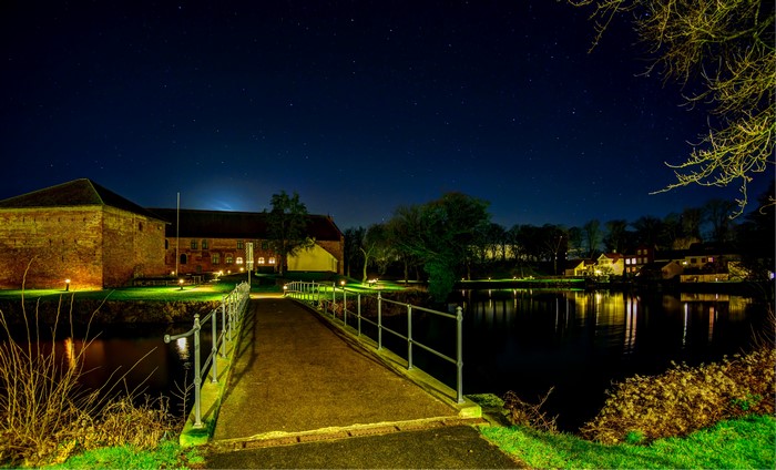 Brick building and bridge over water at night
