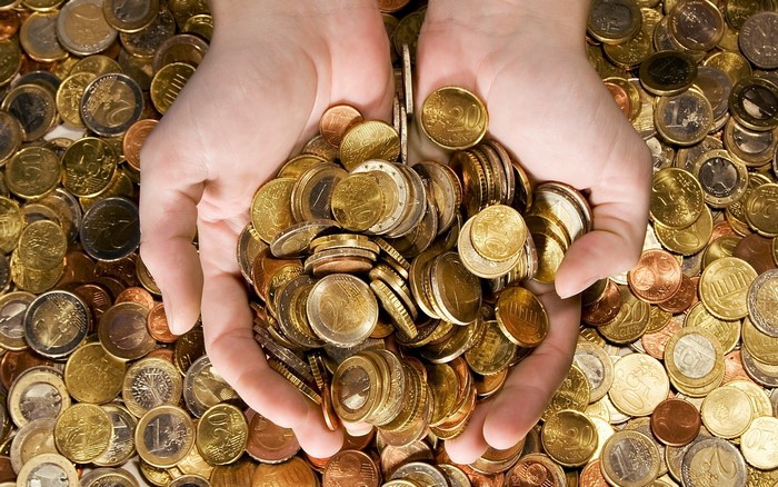 Hands holding a pile of Euro coins