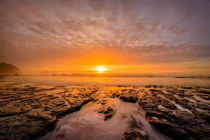 Sunset over rocky shore with ocean waves
