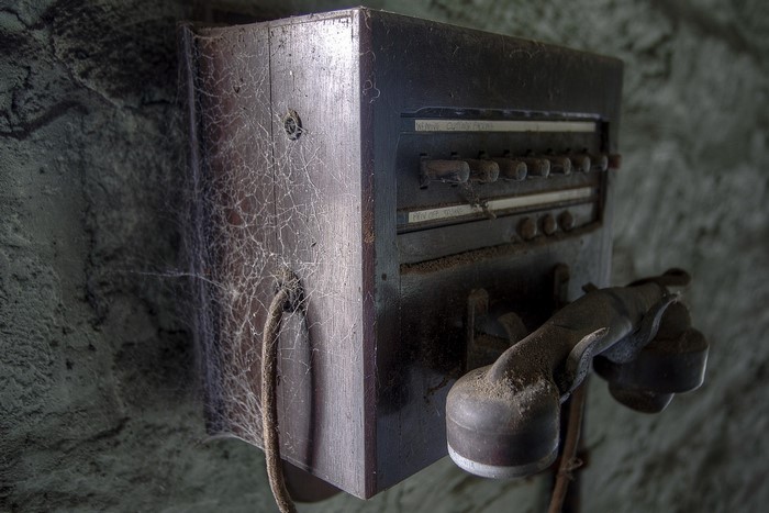 Old wooden telephone covered in cobwebs