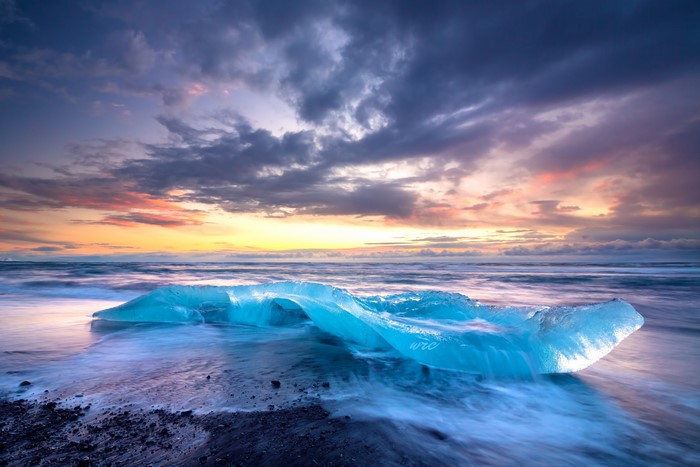 Iceberg on a black sand beach at sunset in Iceland