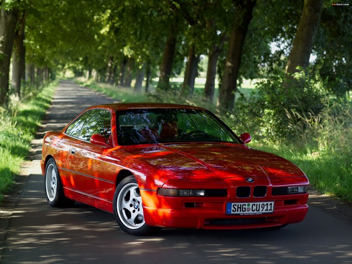 Red BMW M8 E31 on a tree-lined road