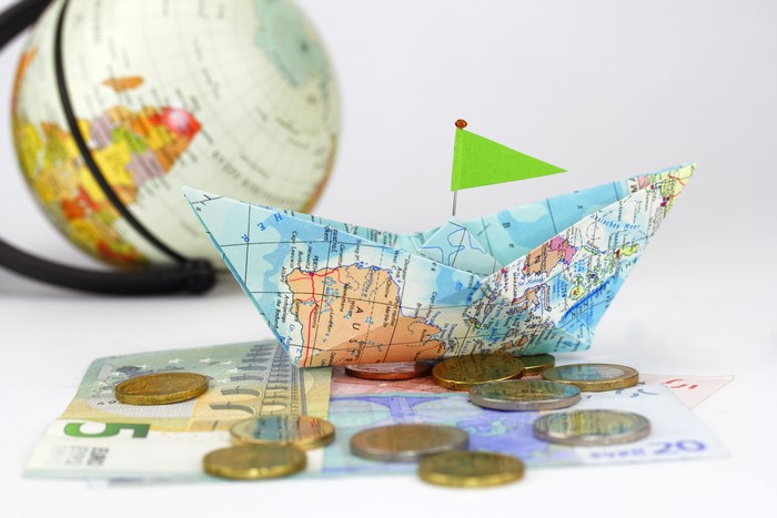 Paper boat with map on money and globe