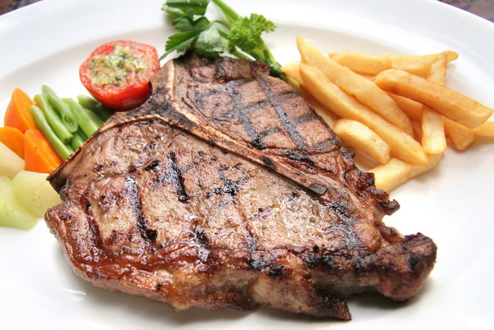 Grilled T-bone steak with french fries and vegetables