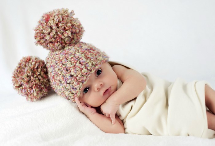 Baby wearing a colorful pom-pom hat