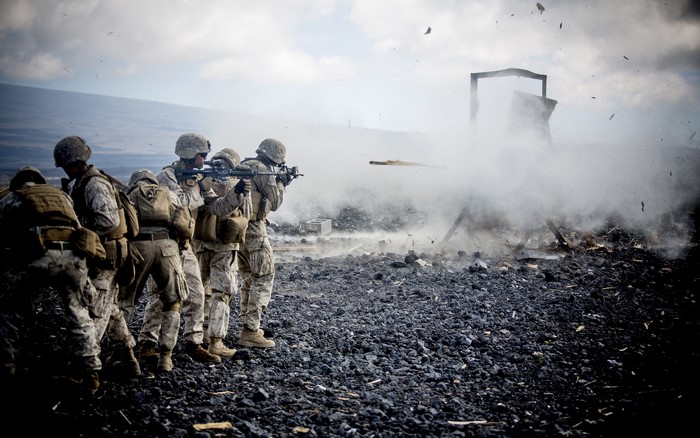 Soldiers firing weapons amidst smoke and debris