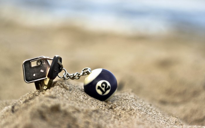 Keys and billiard ball keychain on sand