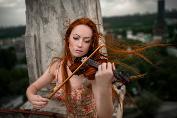 Redhead woman playing violin on a rooftop