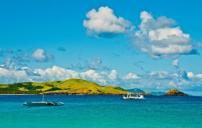 Boats on the sea with green hills and clouds
