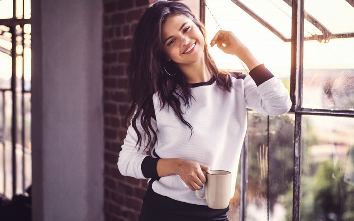 Selena Gomez holding a mug by the window