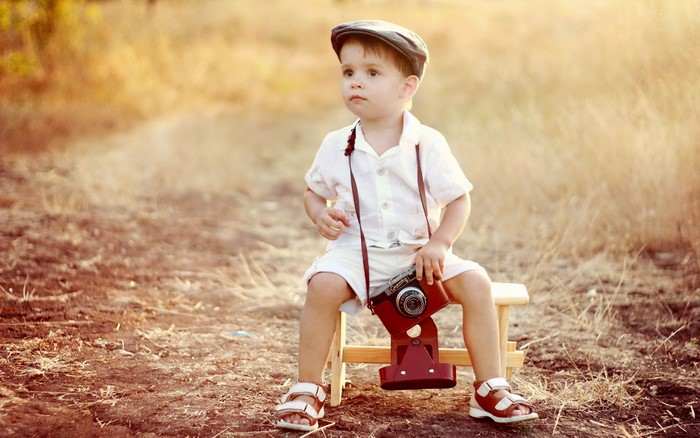 Young boy with a vintage camera sitting outdoors