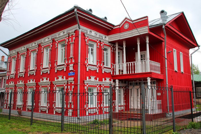 Red wooden house with white ornate carvings in Russia