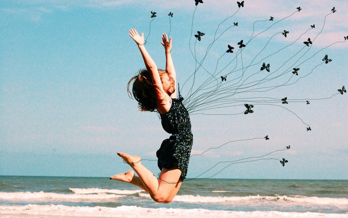 Girl jumping on beach with butterflies