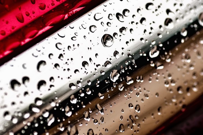 Water drops on a metallic surface with red accents