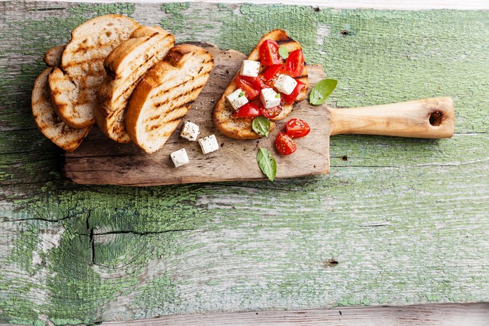 Bruschetta with tomatoes and feta cheese on a wooden board