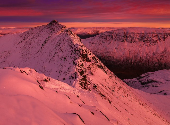 Snow-covered mountains at sunset with pink sky