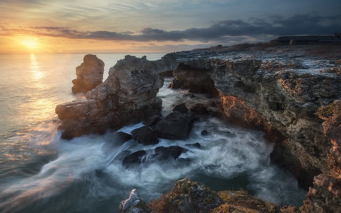 Sunrise over rocky coast with crashing waves