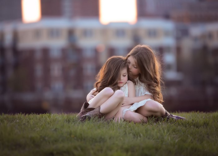 Two young girls sitting on grass