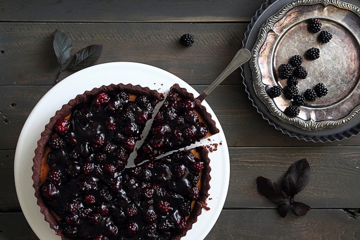 Blackberry tart on a white plate with a serving spatula