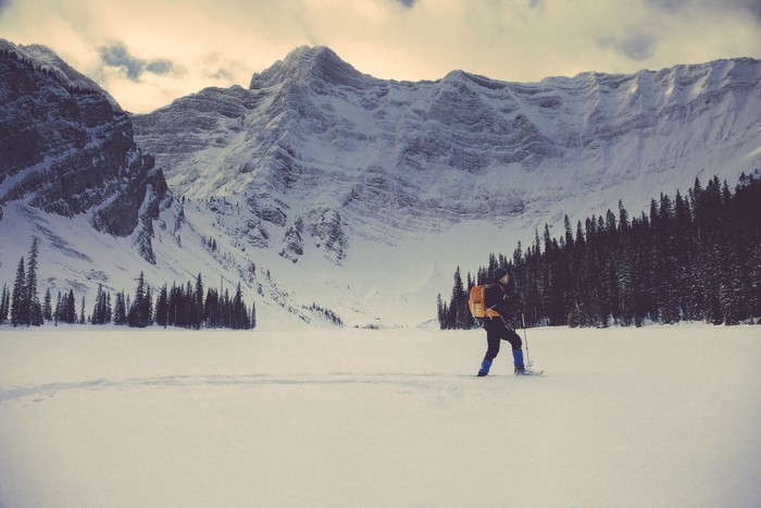 Man snowshoeing in snowy mountains with forest