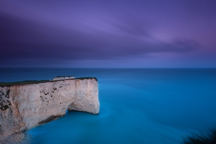 White cliffs and blue sea under purple sky