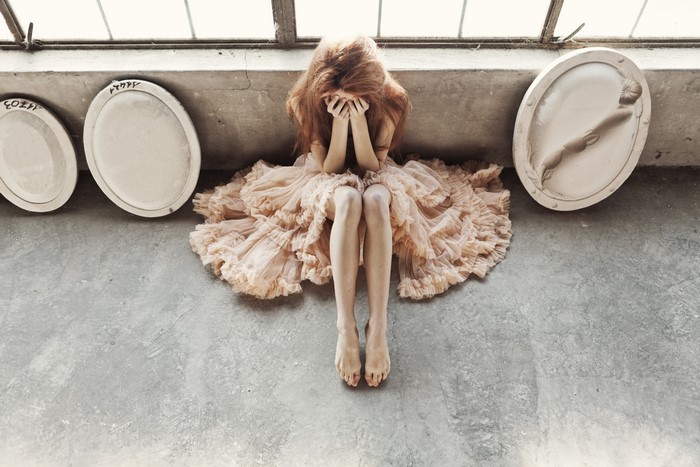 Woman in ruffled dress covering face