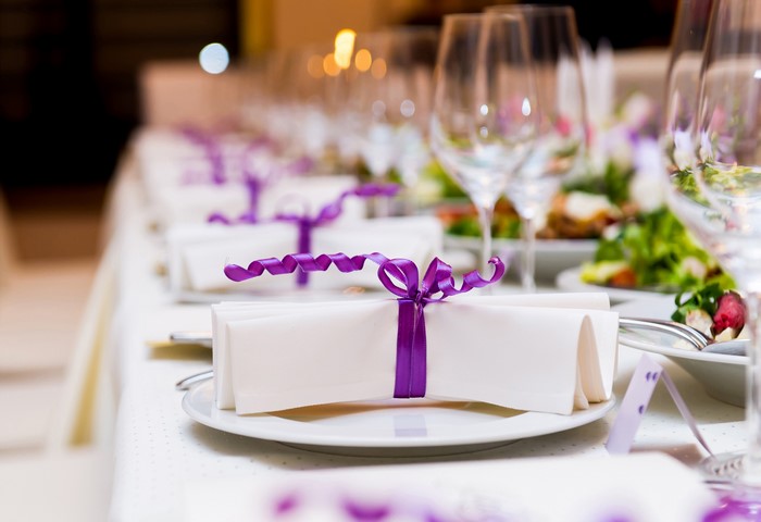 Table setting with white napkins and purple ribbons