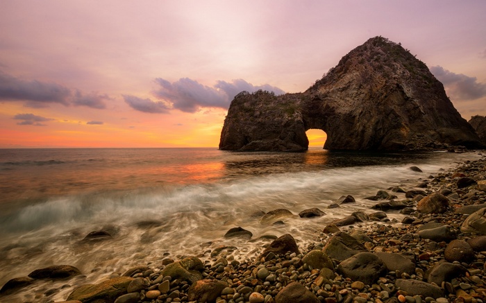 Sunset over rocky beach with sea arch