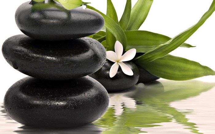 Stacked spa stones with bamboo and flower reflection