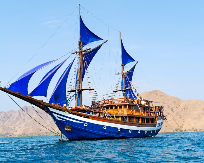 Blue sailing ship with blue sails on the sea