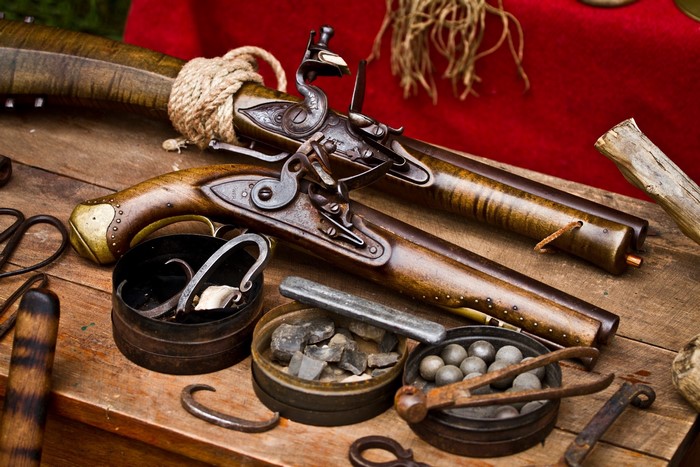 Antique flintlock pistols and ammunition on a wooden table