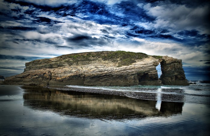 Rock Archway on a Beach Under Dramatic Sky
