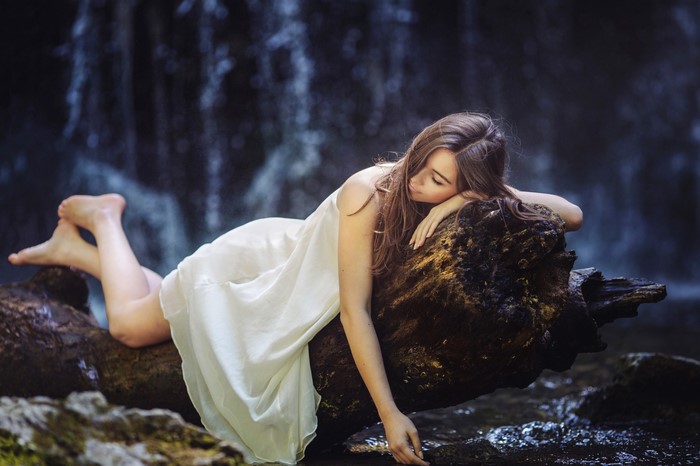 Woman in white dress sleeping on a log