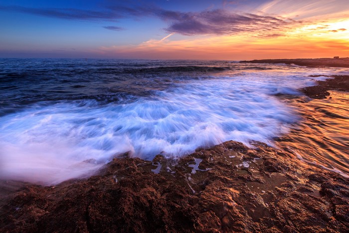 Waves crashing on rocky coast at sunset
