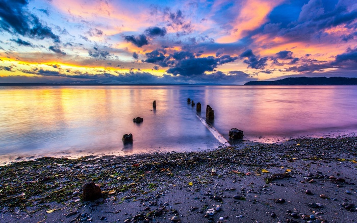 Sunset over a calm body of water with wooden posts