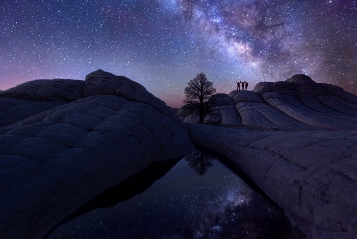 People under the Milky Way in a rocky desert