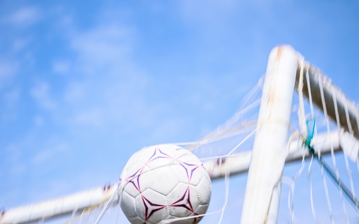 Soccer ball in a net against a blue sky