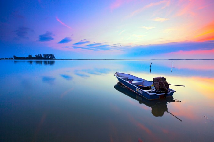 Boat on calm lake at sunset with colorful sky