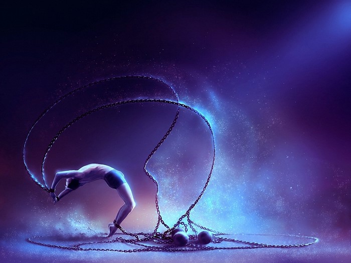 Man chained and bending backwards with chains and light