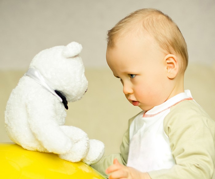 Baby looking at a white teddy bear