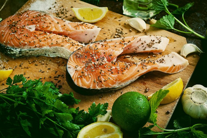 Salmon steaks seasoned with spices on a wooden board with lemon and lime