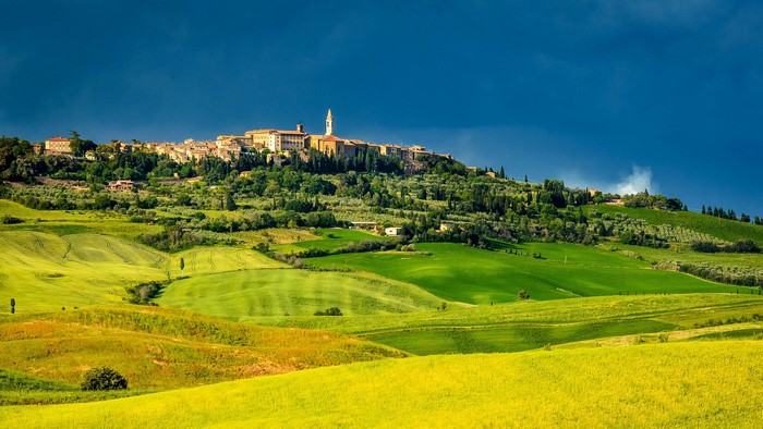 Tuscan village on a hill with rolling green fields