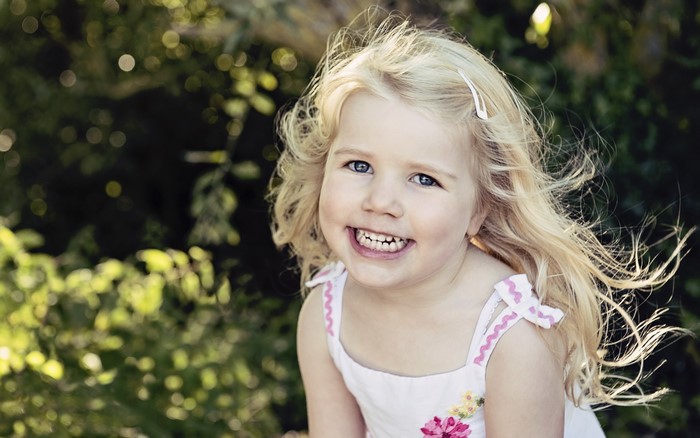Blonde little girl smiling outdoors